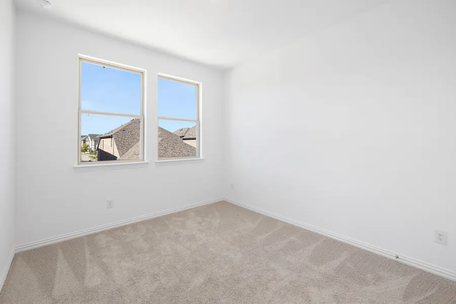 Secondary bedroom with two windows and blue sky views at 4335 Fall Blossom Dr