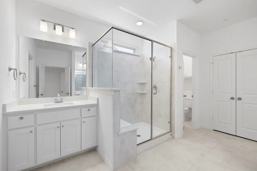 Primary bath with a glass shower and white vanity at 4335 Fall Blossom Dr