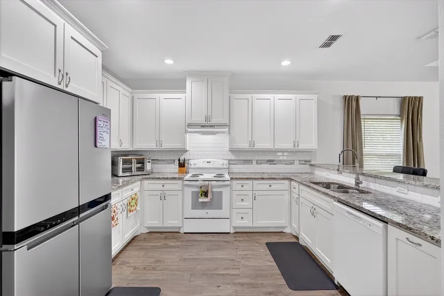 Kitchen with white cabinets, granite counters, and stainless appliances at 4552 Corregidor St