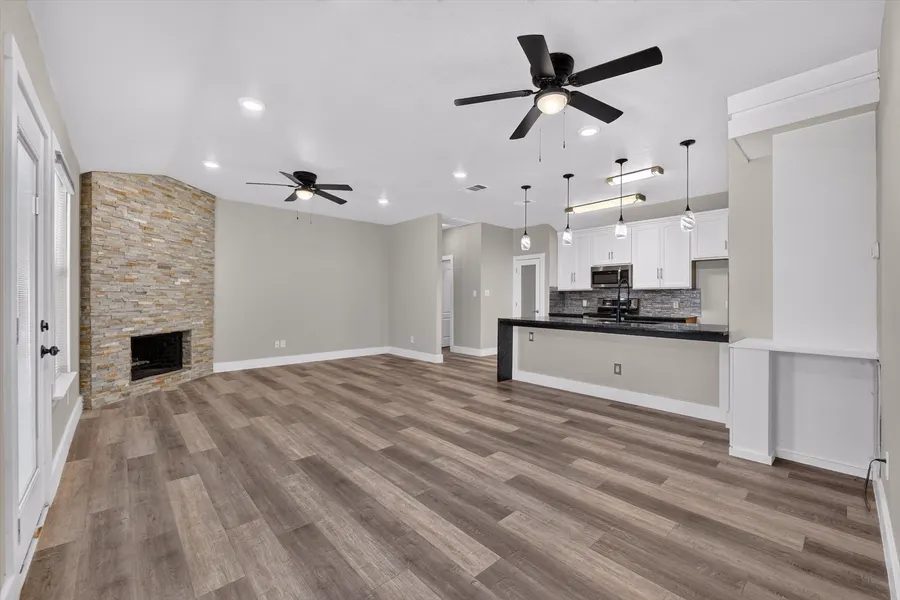 Living room open to the kitchen bar with a stacked stone fireplace at 716 River Hill Ln