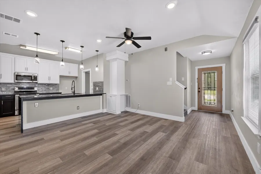 Living and kitchen seen from the entry, with the kitchen peninsula and stair landing at 716 River Hill Ln