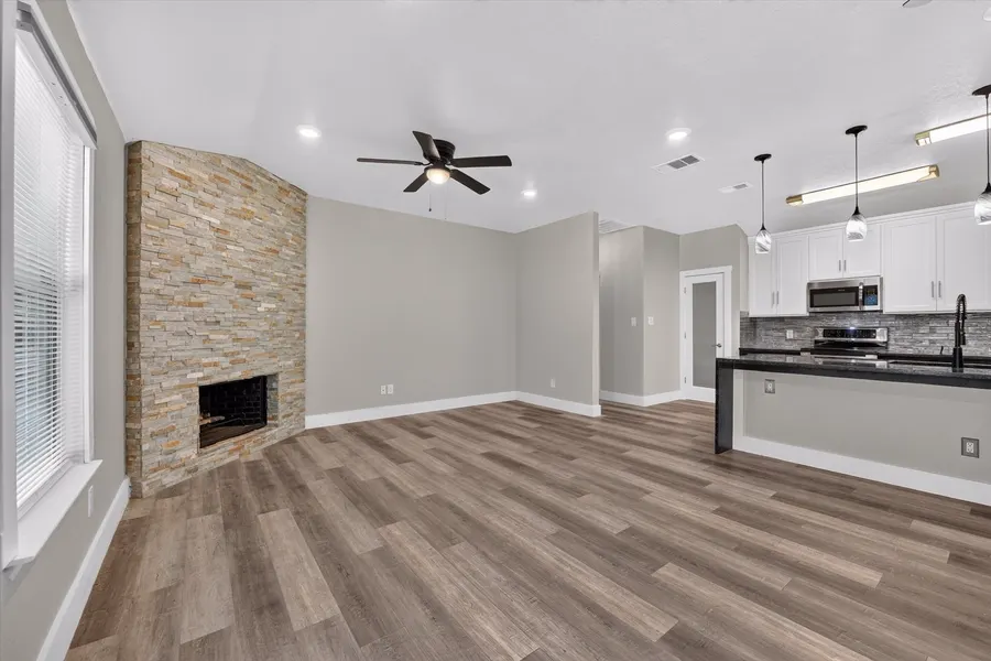 Floor to ceiling stacked stone fireplace with the kitchen beyond at 716 River Hill Ln