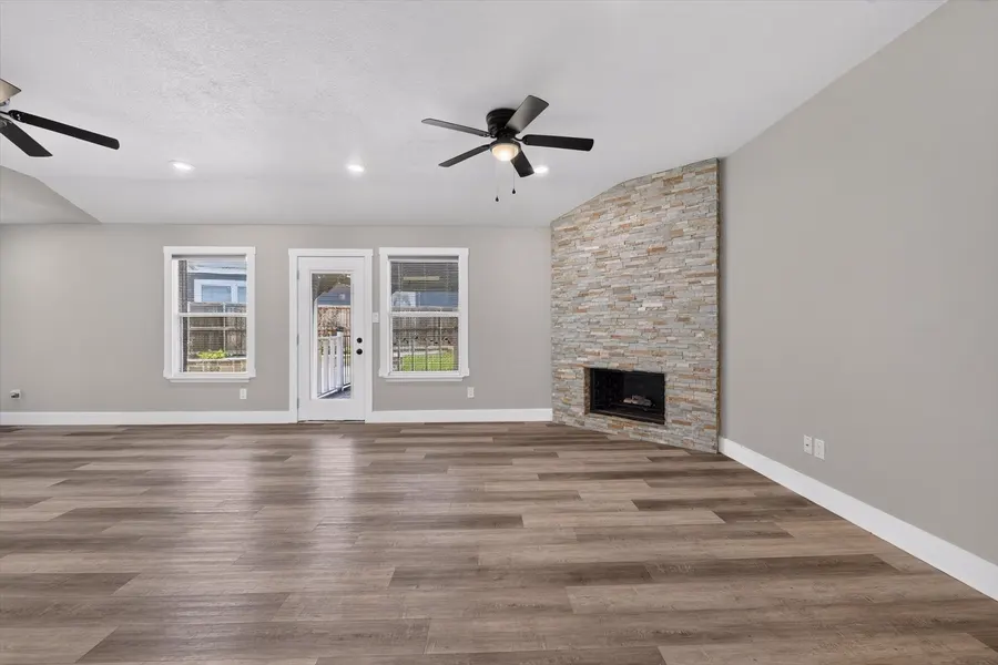 Living room showing the stone fireplace, rear windows, and back door at 716 River Hill Ln