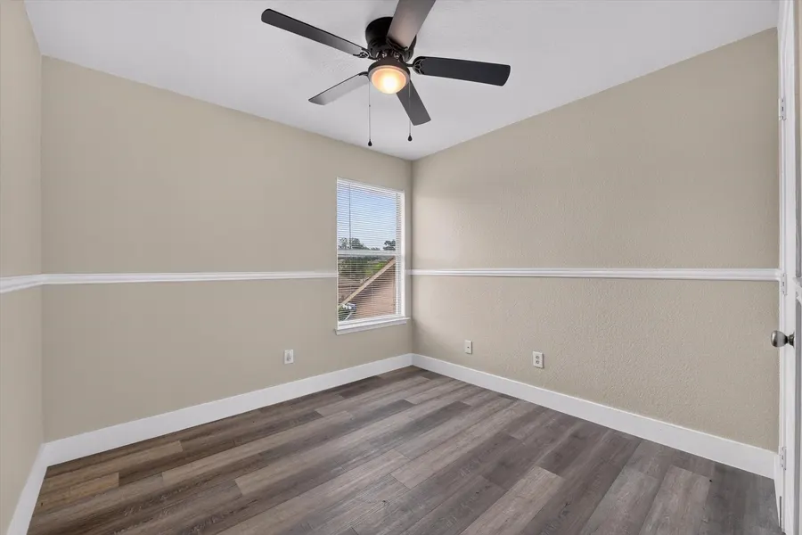 Bedroom with a ceiling fan, chair rail trim, and a window over the yard at 716 River Hill Ln