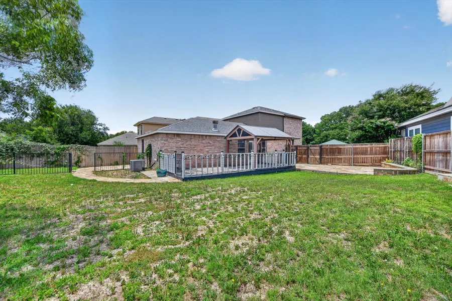 Backyard looking from the rear fence toward the covered porch and deck at 716 River Hill Ln